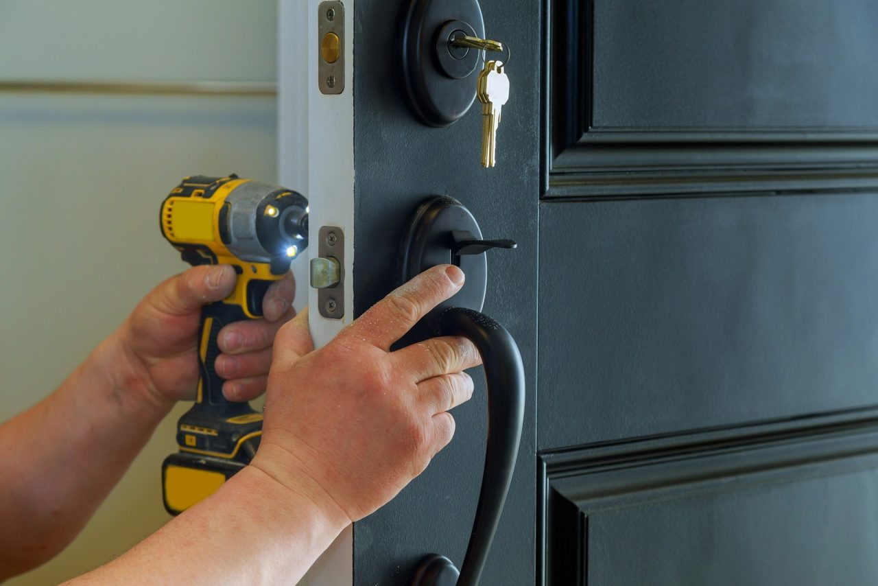 closeup of a professional locksmith installing a new lock on a house exterior door with the inside.jpg